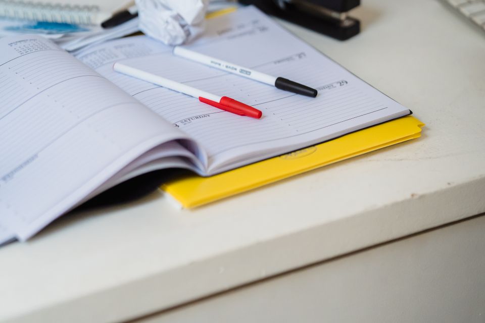 An open planner with pens on a desk