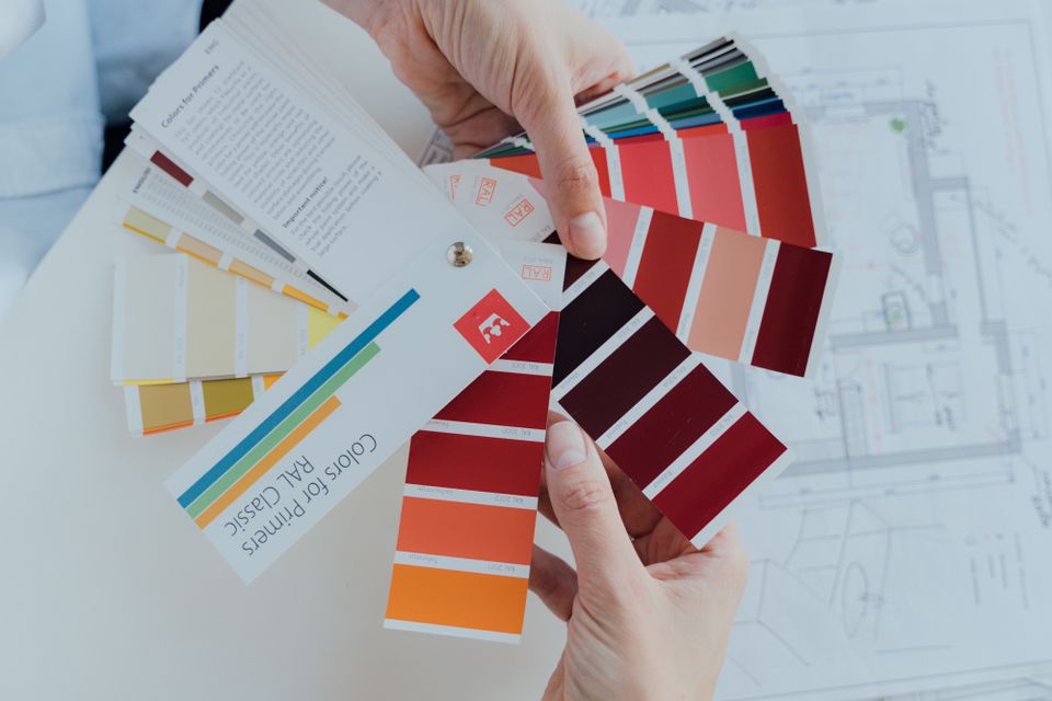 Hands selecting colour swatches over design plans