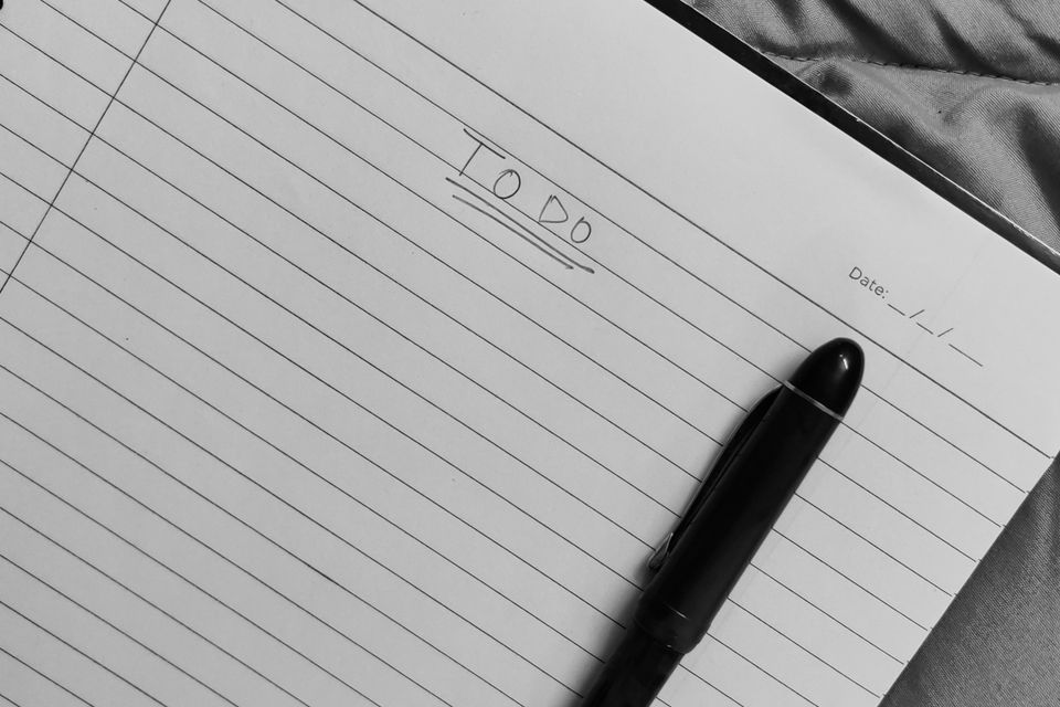 An open to-do notebook with a pen